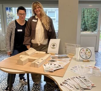 Mareike Gördemann und  Gördemann und Carolin Amthor-Bröker stehen neben einem Holzmodell vom Kolping Gutshof.