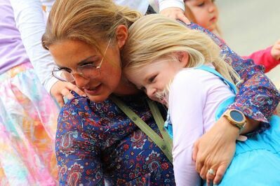 Eine Frau in einem blauen Paisley-Kleid umarmt ein Mädchen.