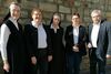 Fünf Personen, darunter zwei Nonnen im schwarzen Habit sowie ein Geschäftsführer und zwei Geschäftsführerinnen von Kolping, stehen nach einem Vertragsabschluss vor einer Steinmauer und lächeln.