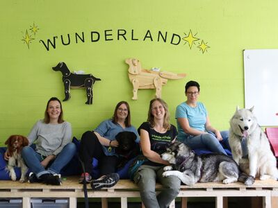 Drei TGB-Lehrerinnen und ihre Trainerin posieren zusammen mit vier Hunden.